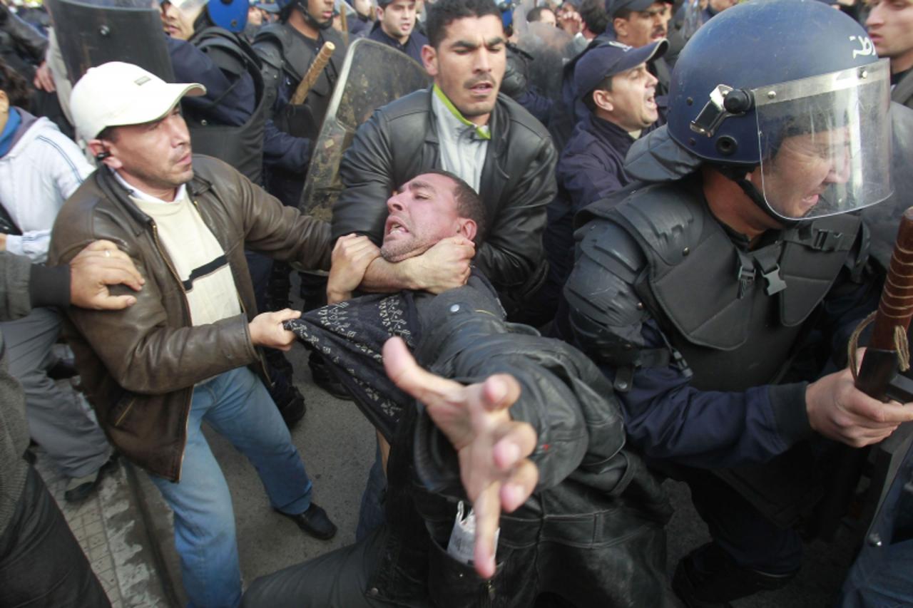\'Plainclothes policemen detain a protester during a demonstration in Algiers February 12, 2011. About 50 people shouted anti-government slogans in a square in Algeria\'s capital on Saturday but were 