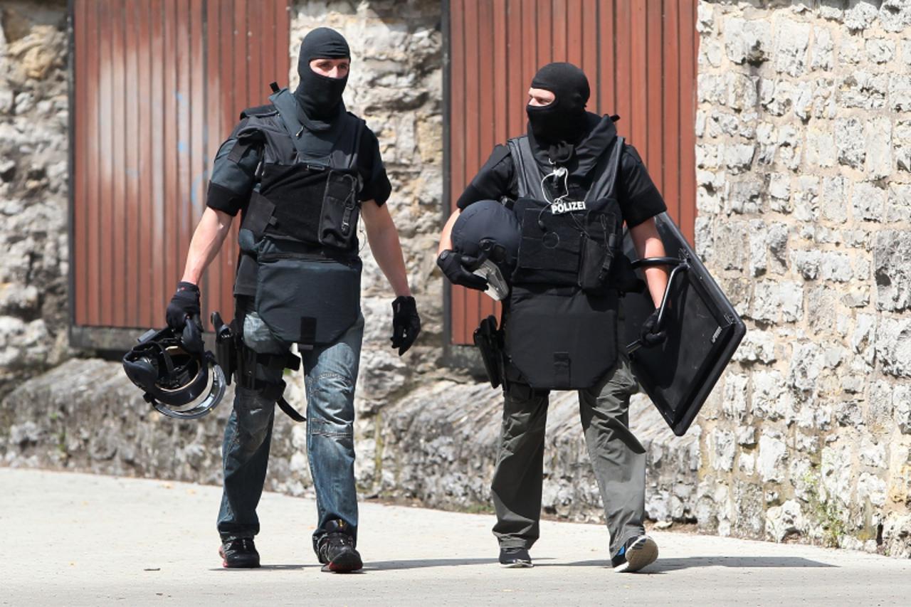 'Members of policeman leave the area where a gunman had taken several people, including a bailiff, hostage during a home eviction in Karlsruhe, southwestern Germany, on July 4, 2012.  A police spokesm