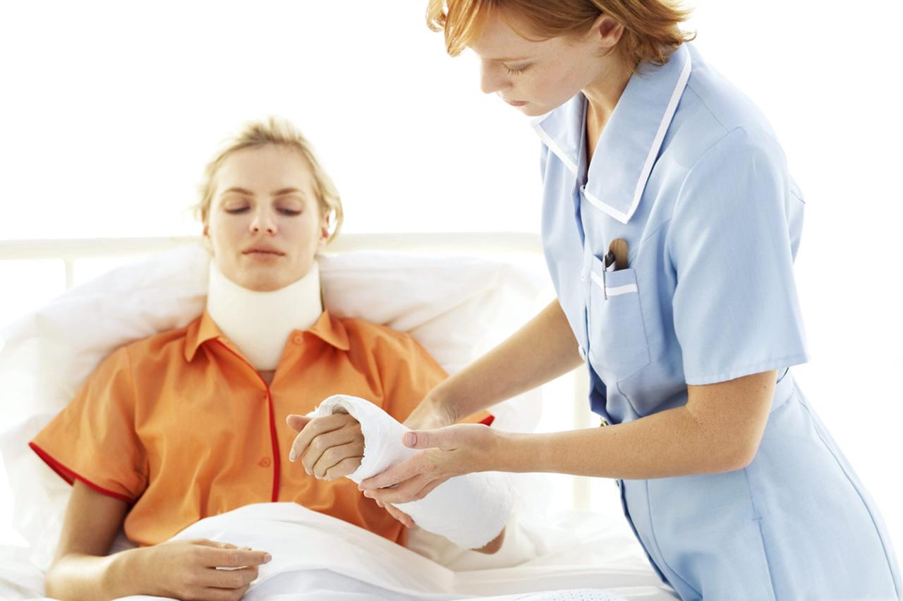 Young Nurse Tending to Young Woman with Neck Brace and Arm Cast --- Image by © Royalty-Free/Corbis