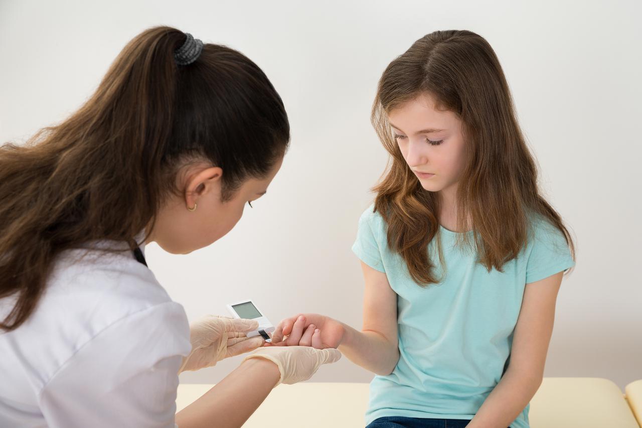 Doctor In Labcoat Measuring Blood Sugar Level Of Girl With Glucometer