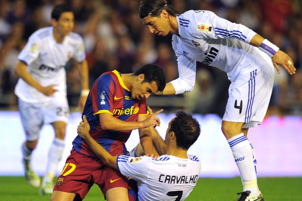 'Barcelona\'s forward Pedro Rodriguez (L) argues  with Real Madrid\'s Portuguese defender Ricardo Alberto Carvalho (C) next to Real Madrid\'s defender Sergio Ramos during their Spanish Cup final match