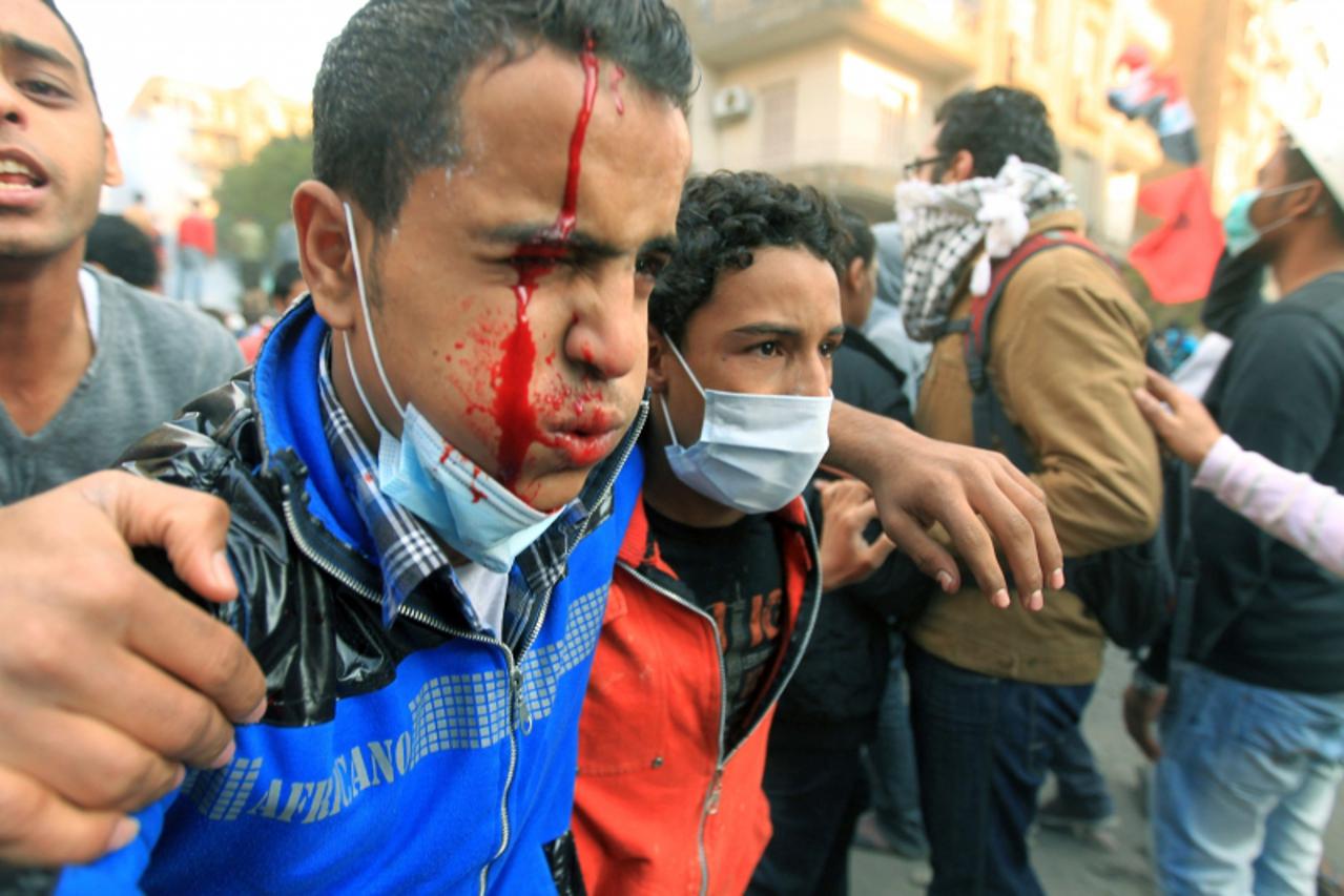 'An injured Egyptian protester is helped away during clashes with security forces on the third day at Tahrir Square in Cairo on November 21, 2011.  Fresh clashes erupted in Cairo\'s Tahrir Square betw