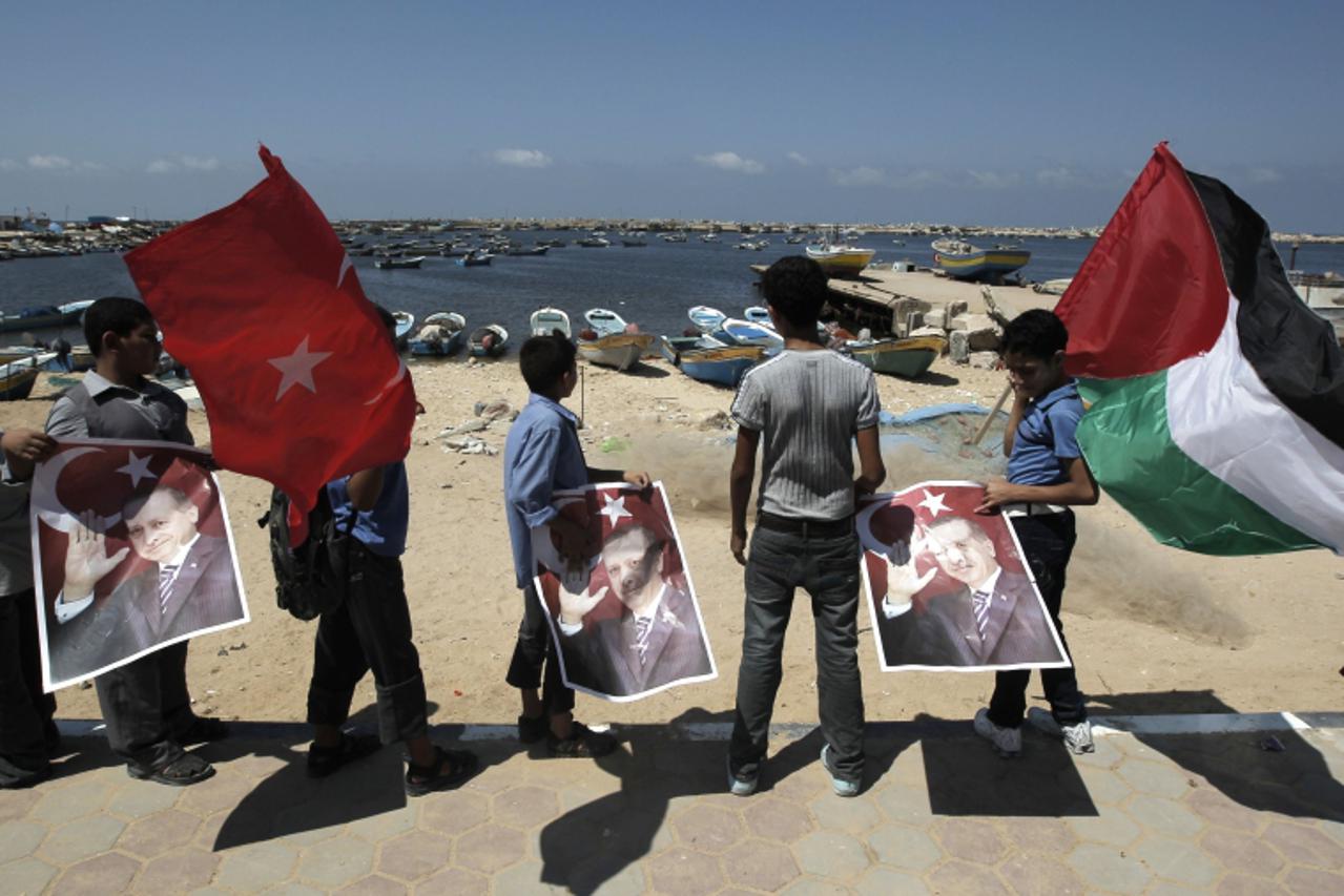 'Palestinian students stand at the port in Gaza  city holding pictures of Turkish Prime Minister Recep Tayyip Erdogan and the Turkish (L) and Palestinian flag following a rally beckoning him to visit 