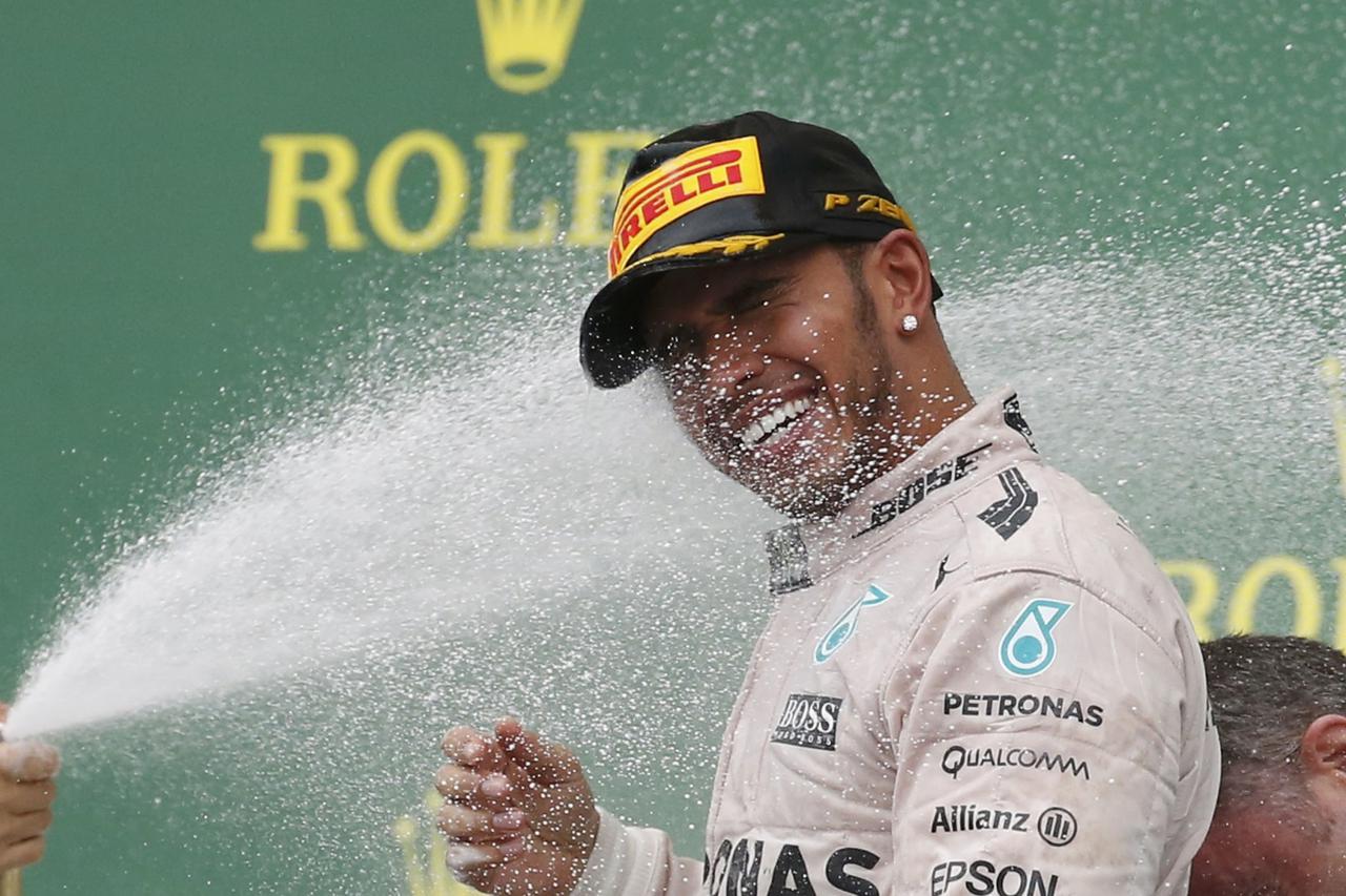 Third placed finisher Ferrari Formula One driver Sebastian Vettel of Germany (off camera) sprays champagne on race winner Mercedes driver Lewis Hamilton of Britain following the U.S. F1 Grand Prix at the Circuit of The Americas in Austin, Texas October 25