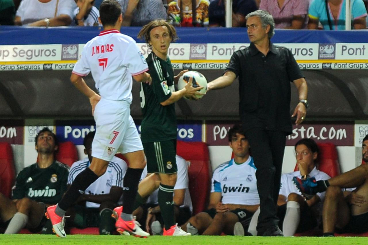 'Real Madrid's coach Jose Mourinho (R) gives the ball to Real Madrid's Luka Modric (C) during the Spanish league football match between Sevilla FC and Real Madrid on September 15, 2012 at the Ramon 