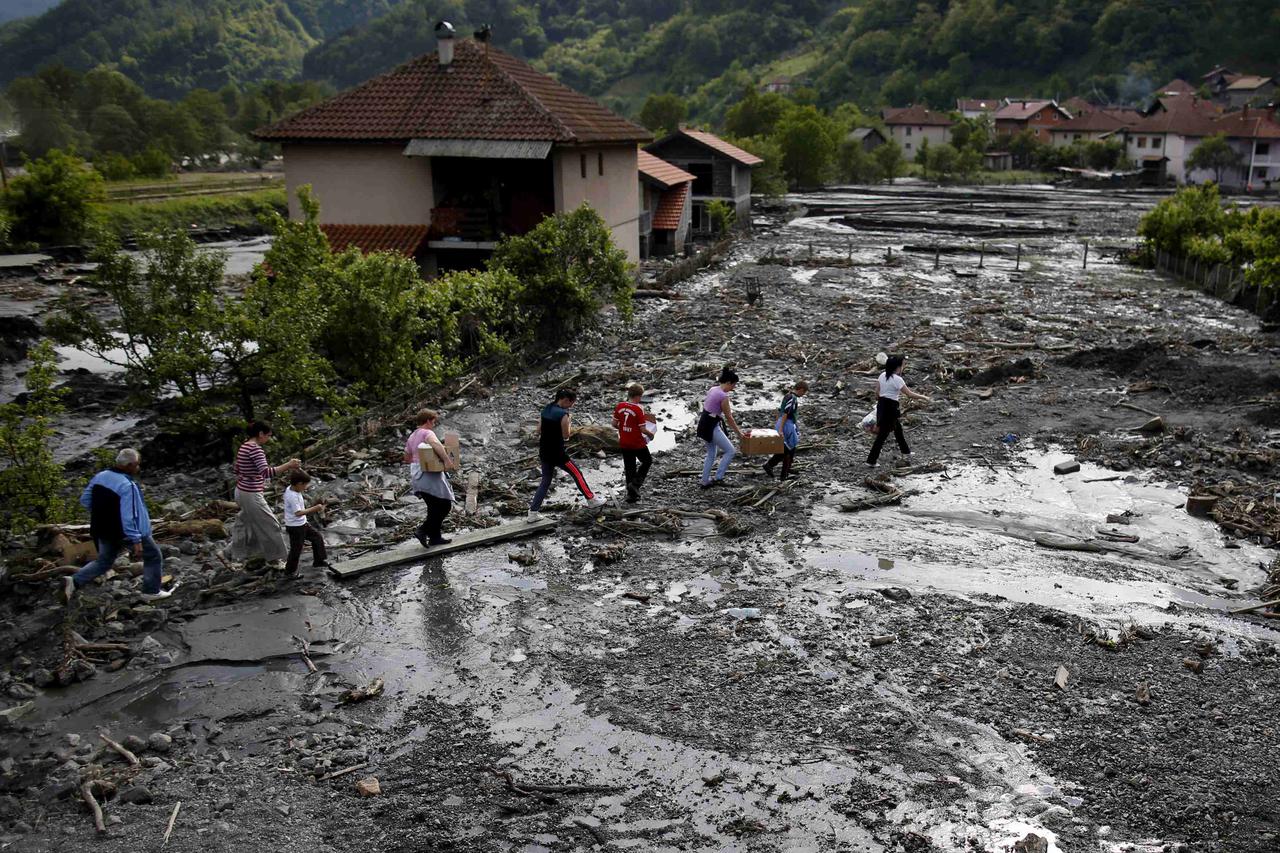 People carry food received from humanitarian organizations in Topcic Polje, May 20, 2014. At least 40 people have died in Serbia, Bosnia and Croatia, after days of the heaviest rainfall since records began 120 years ago caused rivers to burst their banks 