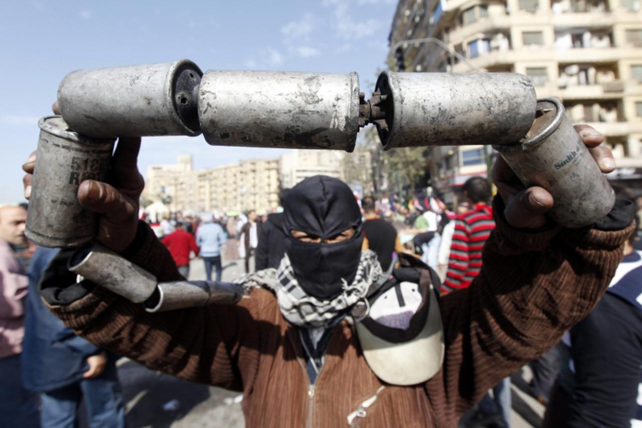 'A protester opposing Egyptian President Mohamed Mursi holds empty tear gas canisters, which was thrown earlier by riot police, during clashes along Sheikh Rihan street near Tahrir Square in Cairo Jan