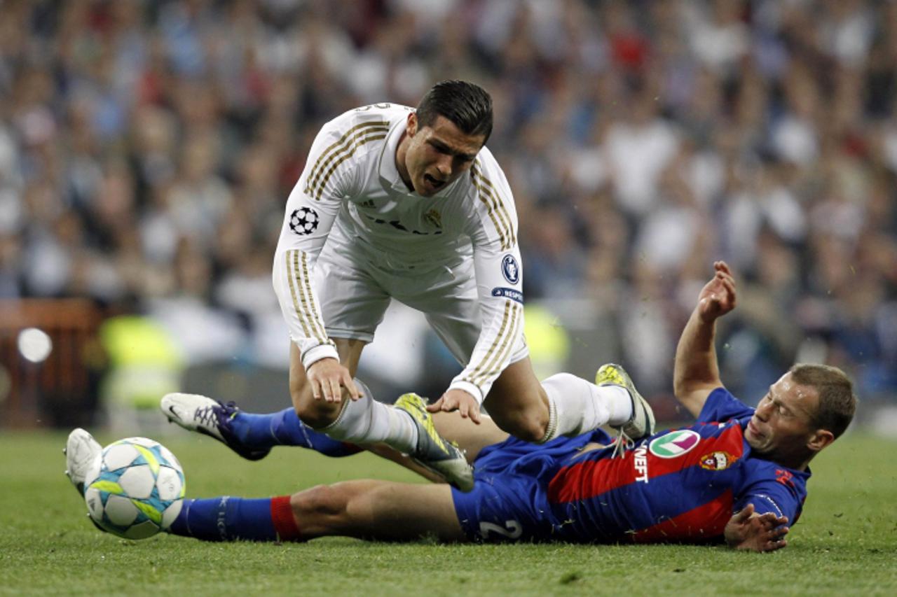 'Real Madrid\'s Cristiano Ronaldo (L) is tackled by CSKA Moscow\'s Vasili Berezutski during their Champions League round of 16 second leg soccer match at Santiago Bernabeu stadium in Madrid March 14, 